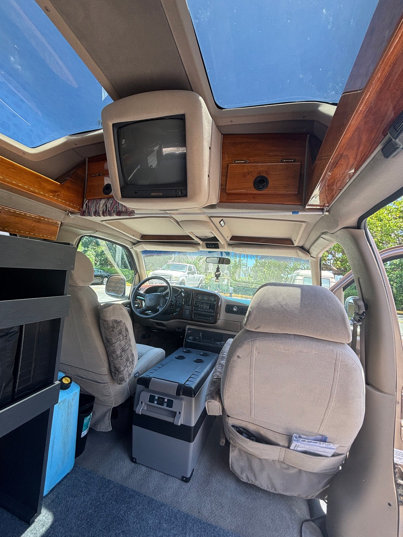 Interior of a spacious RV rental. Features include dual skylights, an overhead TV, and a portable fridge for comfortable travel.