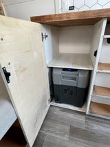 Inside an RV rental: open cabinet reveals a compact portable fridge. Perfect for efficient travel food storage on the go.