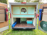 RV rental: Inside a neat cargo trailer conversion, ready for camping with chairs, cooler, & outdoor gear.