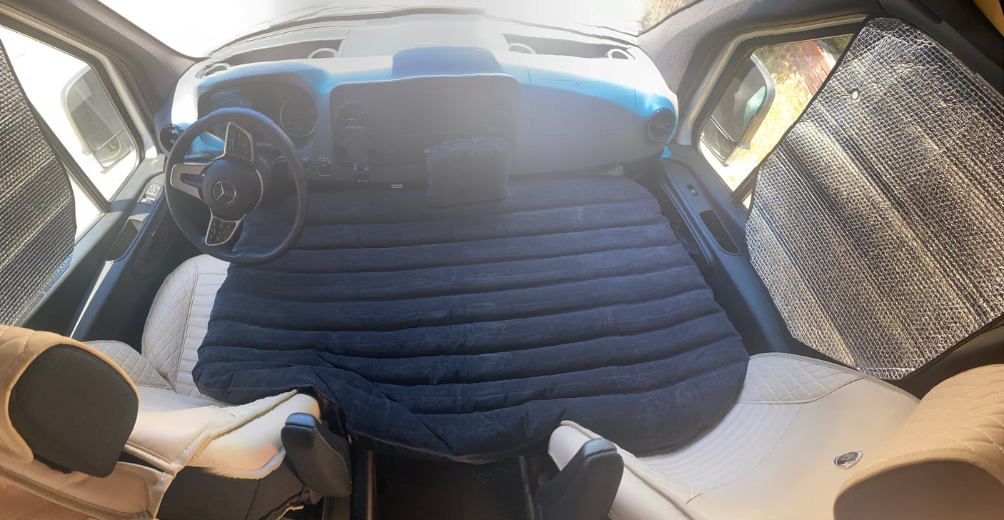 RV rental van interior showing a black air mattress, creating a cozy sleeping setup with sunshades.