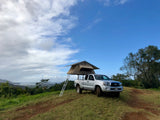 RV rental option: Silver truck with rooftop tent set up on a grassy hill, offering scenic views for your adventure.