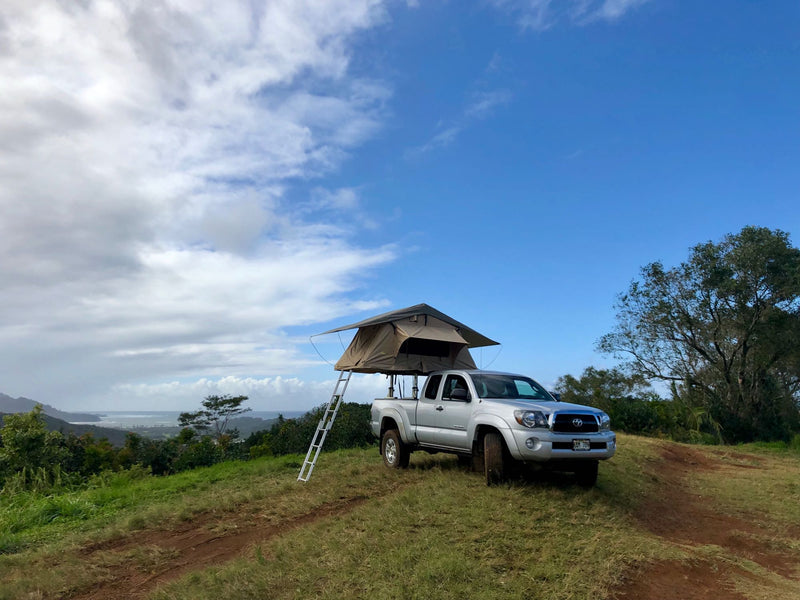 RV rental option: Silver truck with rooftop tent set up on a grassy hill, offering scenic views for your adventure. — photo 6