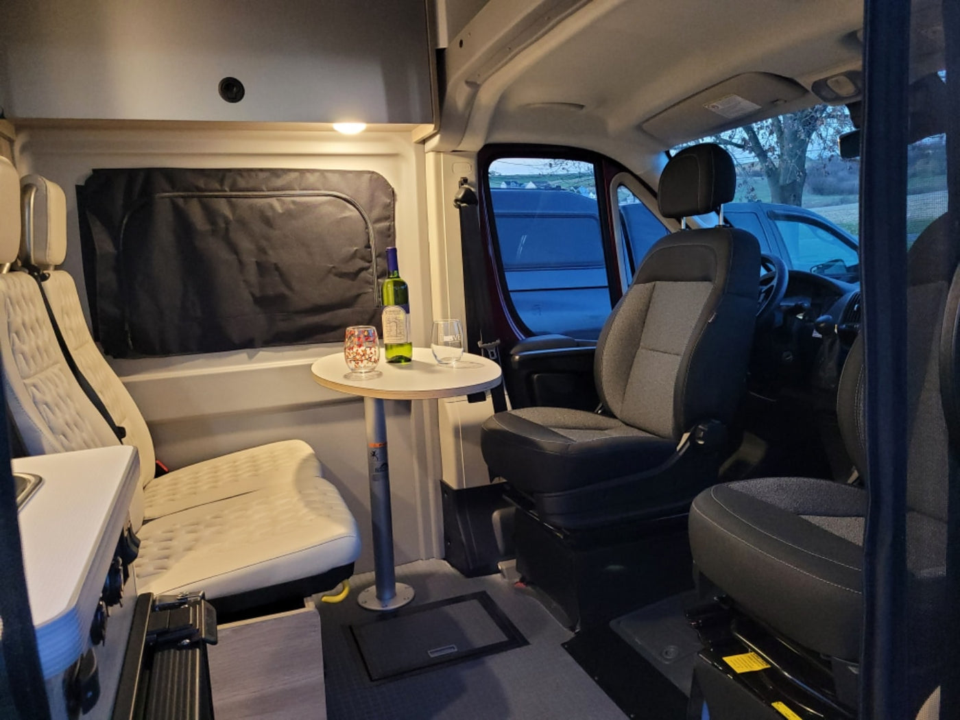 Cozy RV rental interior: A spacious camper van with seating, a table for drinks, and a small kitchenette, perfect for travel. — photo 3