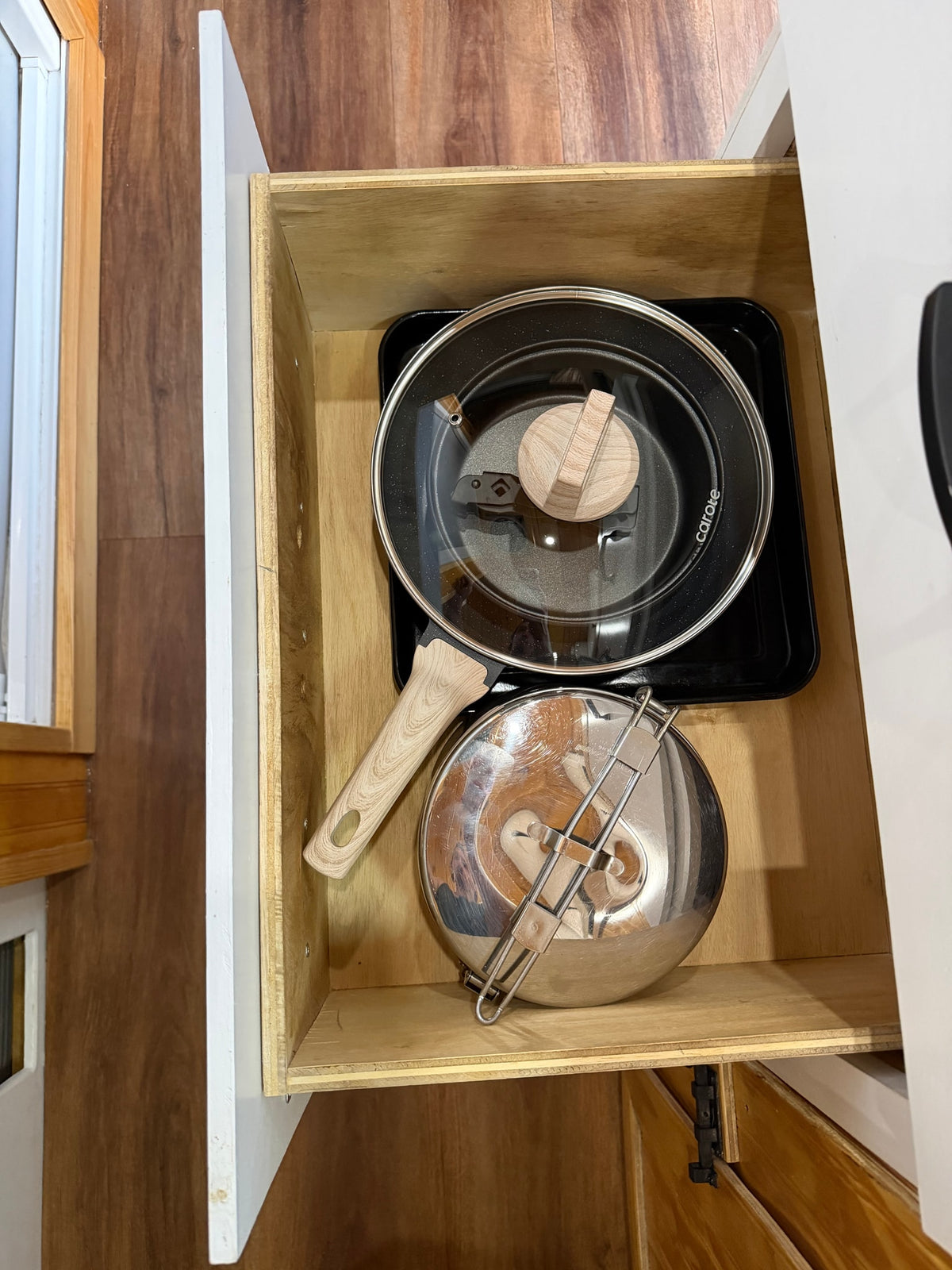 Neatly organized kitchen drawer in an rv rental, featuring a black pot with a glass lid and a stainless steel pot with a folding handle. — photo 11
