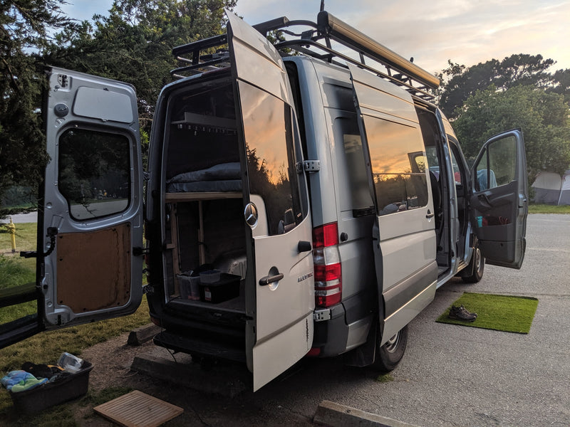 A detailed view of an RV rental Sprinter camper van at dusk, with all doors open, showing its ready-to-camp setup. — photo 26