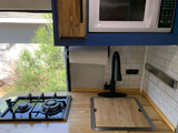 RV rental kitchen: Compact design with a stovetop, sink, microwave, and bright window view.