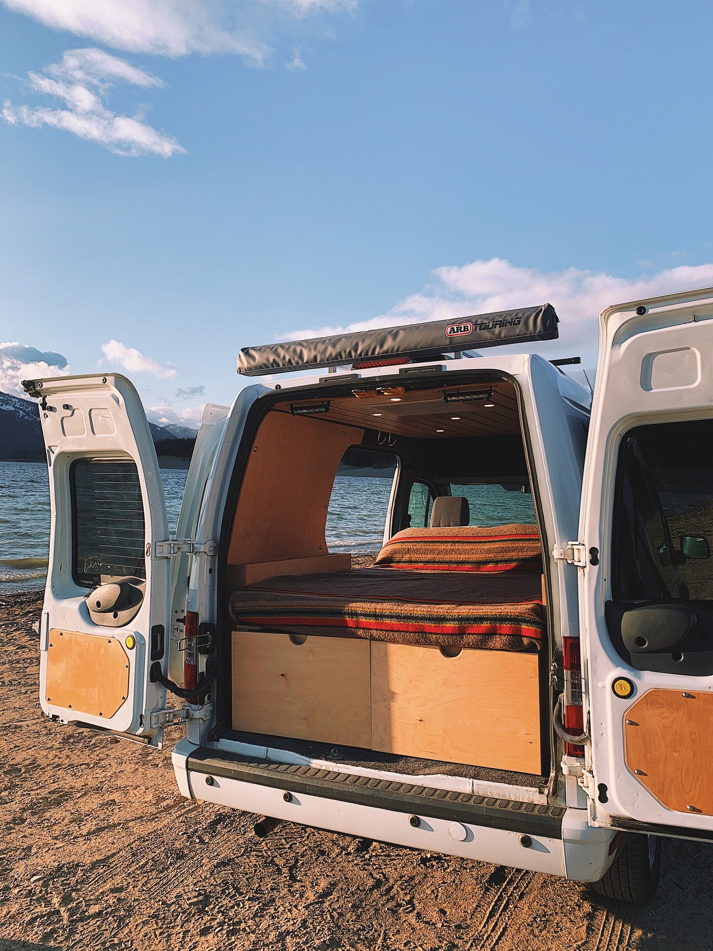 Experience van life! This cozy camper van, perfect for an RV rental, offers stunning lakeside views & a custom interior.