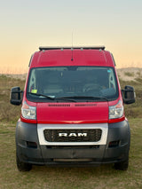 Front view of a red Ram ProMaster camper van with roof rack, an ideal rv rental for your van life adventure.