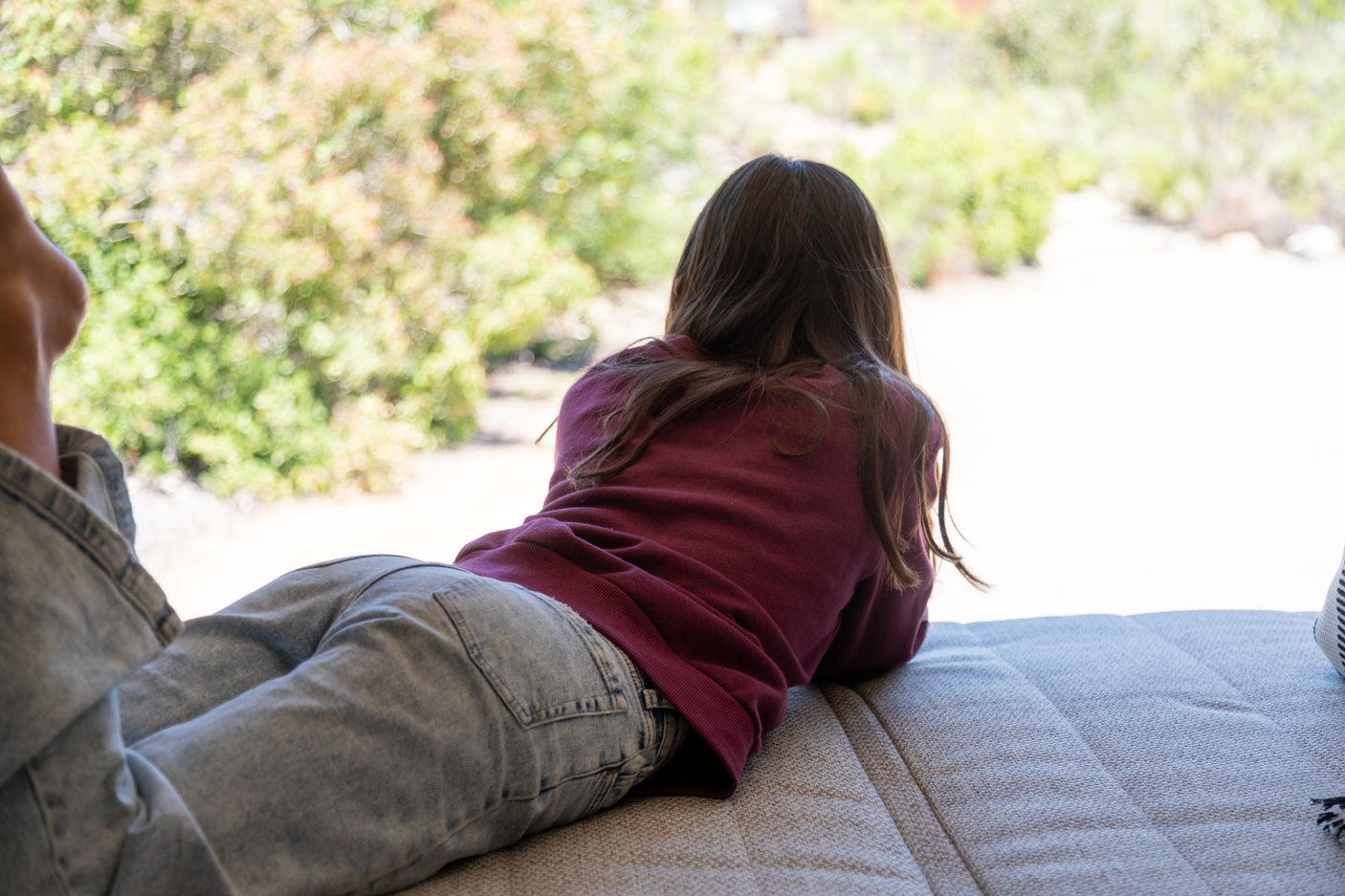 Relaxing RV rental view: A person lies on a bed, looking out at a blurry green landscape, perfect for serene travel.