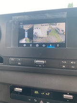 Inside an RV rental, the dashboard screen displays a 360-degree camera view, alongside infotainment and climate controls.