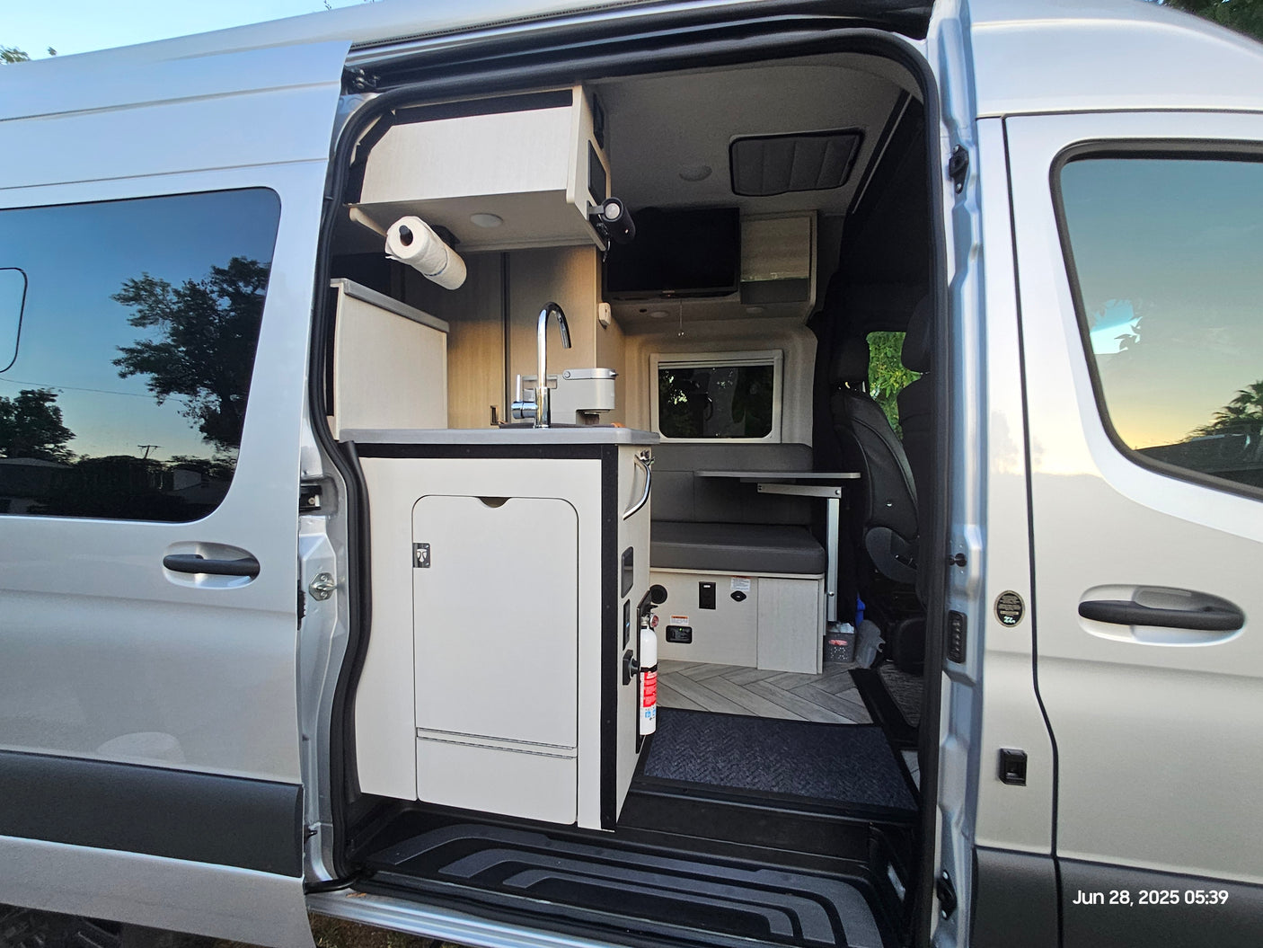 RV rental: Spacious interior of a modern silver camper van, featuring a kitchen and dining area.