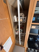 RV rental kitchen: open cabinet with a compact pull-out pantry organizer storing spices and supplies next to the stove.