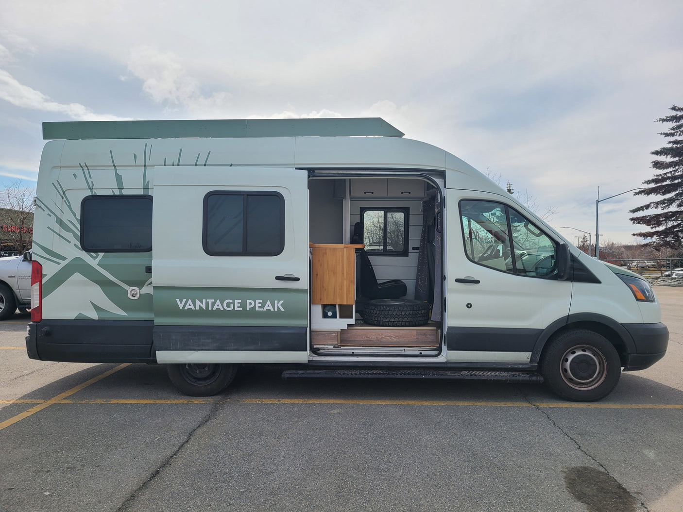 A white Ford Transit camper van conversion, branded 'Vantage Peak', available as an RV rental.