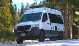 Adventure-ready Mercedes Sprinter camper van for RV rental, parked on snow in a pine forest. Perfect for winter travel.