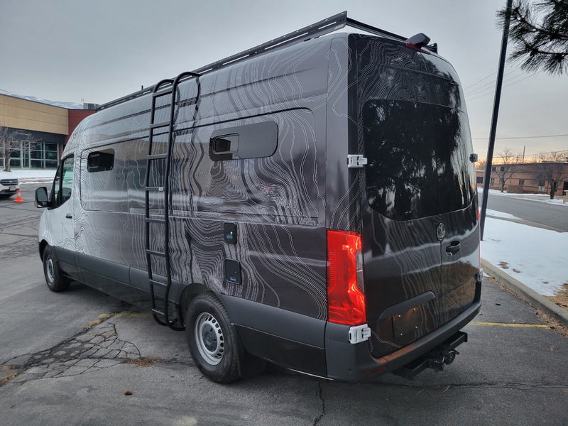 Explore in style: This dark custom topographic-wrapped RV rental van features a roof rack and side ladder for adventure. — photo 9