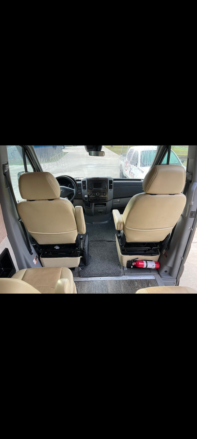 RV rental interior: View from the back showing tan captain's chairs, dashboard, and a fire extinguisher for safety. — photo 7