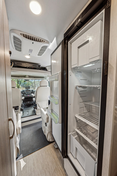 Explore this rv rental's organized interior. Features an open refrigerator, comfortable swivel seats, and an AC unit for comfort.