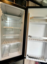 Clean, empty RV rental refrigerator, ready for use. Features organized shelves and door bins.