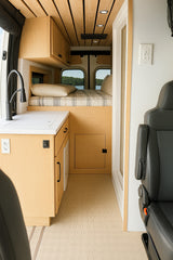 Step into this bright RV rental! Modern camper van interior with a cozy bed, sleek kitchen, and scenic lake views from the rear.