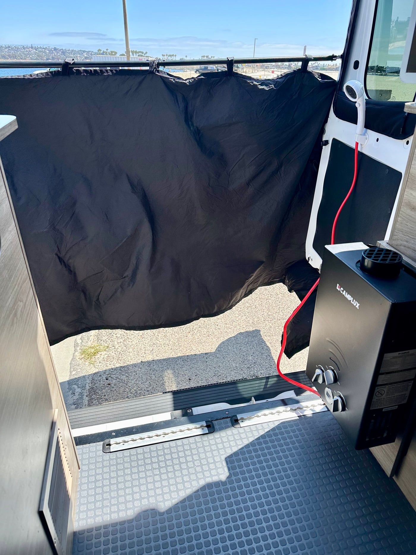 This RV rental features a convenient outdoor shower setup with a portable Camplux water heater, privacy curtain, and hose, perfect for beachside cleaning. — photo 18