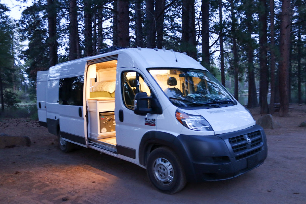 Cozy RV rental camper van parked in a forest at dusk