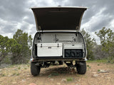 Inside this RV rental, an off-road camping trailer features an open hatch, YETI cooler, and organized gear.