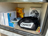 Organized RV rental storage shows camping essentials: portable fan, Camco gear, and leveling blocks ready for adventure.