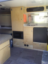 Explore this efficient rv rental interior: a light wood kitchen with sink and fridge, plus a cozy patterned living space.