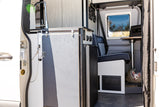 RV rental interior with a functional kitchenette, control panel, seating, and a small dog in a cozy bed. Your mobile home!