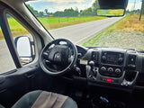 POV from an RV rental camper van, showcasing the dashboard, steering wheel, and a rural road stretching into the distance.