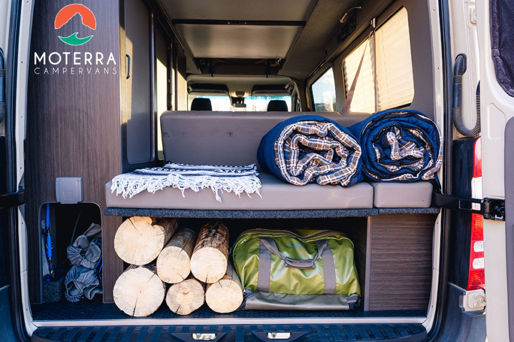 Moterra campervan RV rental interior: organized storage for camping gear, firewood, and comfy blankets. Ready for adventure!