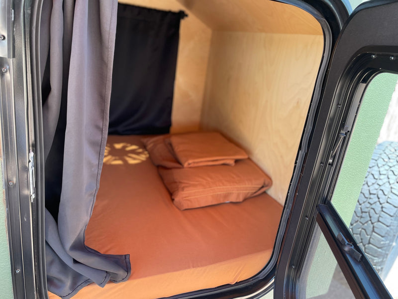 Cozy rv rental sleeping area with orange bedding, wooden walls, and privacy curtains. Ideal for compact travel. — photo 4