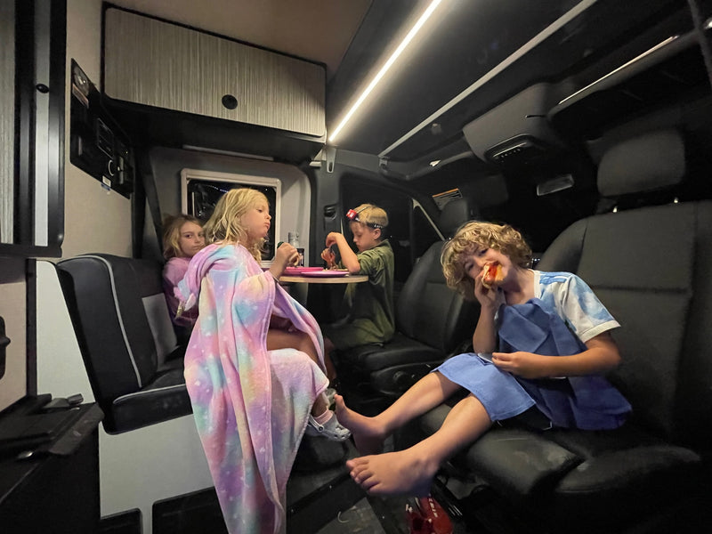 Four kids, one with a hot dog, cozy inside an RV rental for dinner. Family travel comfort for everyone! — photo 3