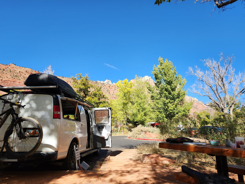 Adventure-ready RV rental: white van with bike rack at scenic red rock campsite with autumn trees. — photo 5