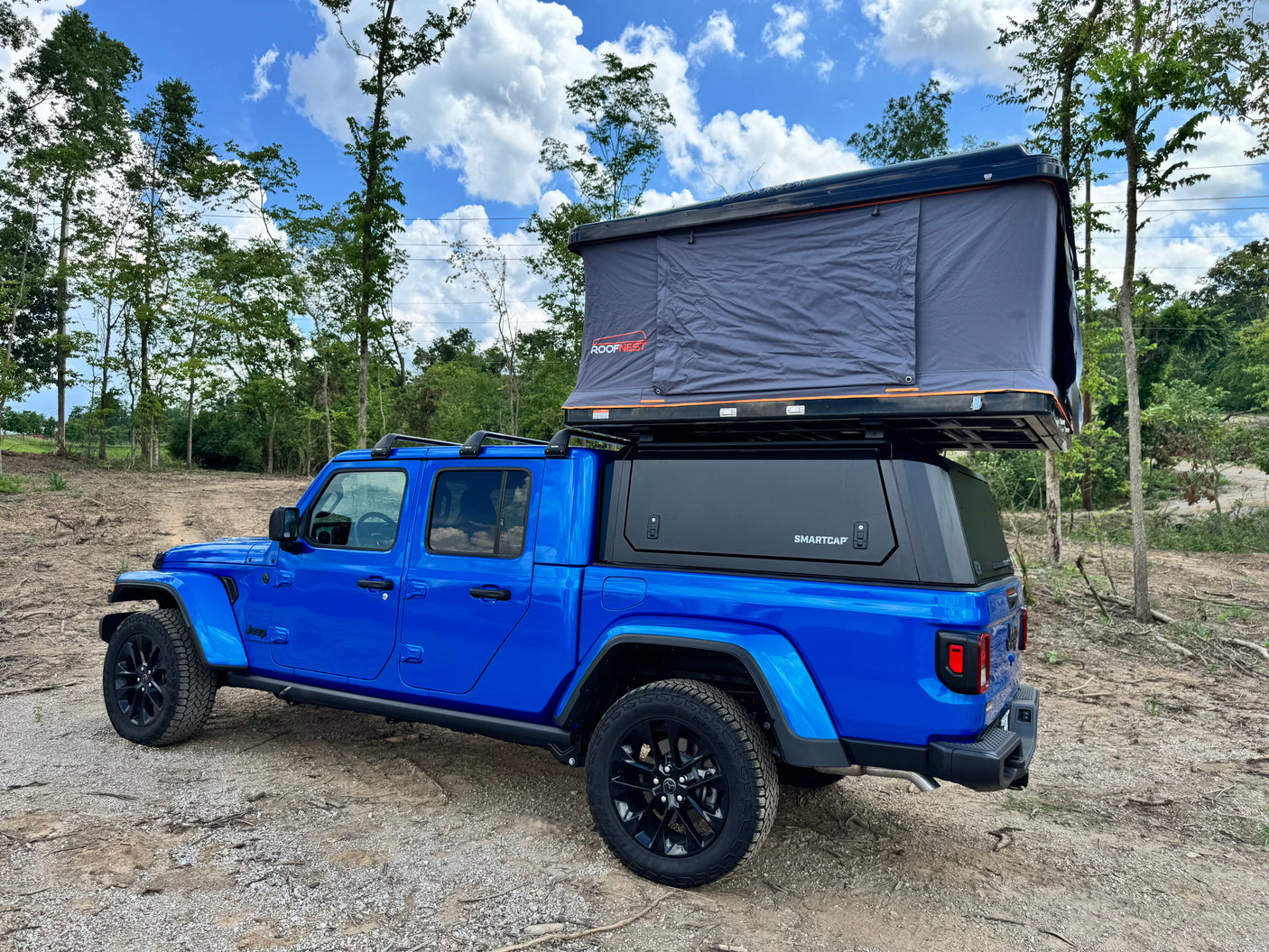 Blue Jeep Gladiator with a Roofnest tent and Smartcap. An exciting RV rental for your overlanding and camping adventures.