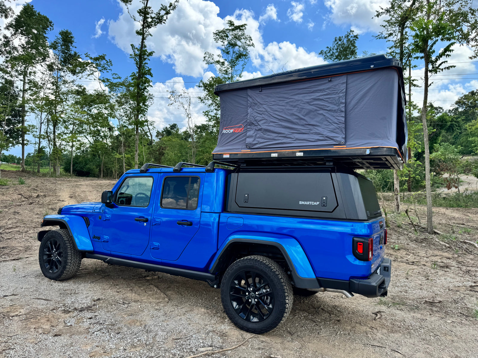 Blue Jeep Gladiator with a Roofnest tent and Smartcap. An exciting RV rental for your overlanding and camping adventures.