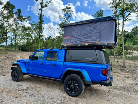 Blue Jeep Gladiator with a Roofnest tent and Smartcap. An exciting RV rental for your overlanding and camping adventures.