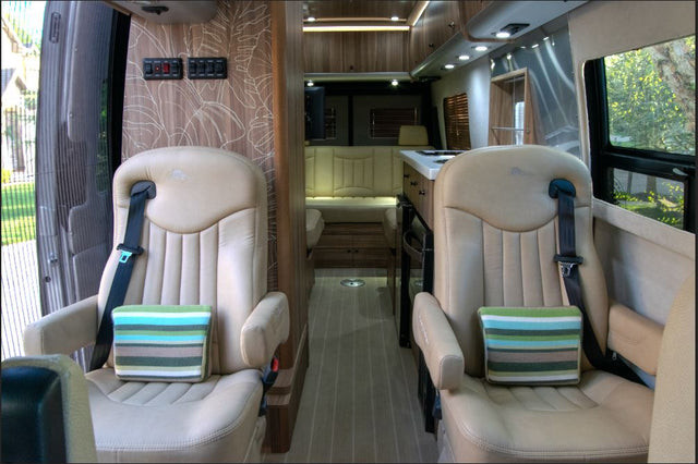  an aisle leading to a compact kitchen & living area.|Two views of an RV rental wet bath