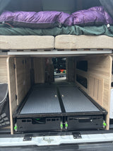 This RV rental features organized rear storage: dual Solis pull-out trays beneath a bed with cushions.