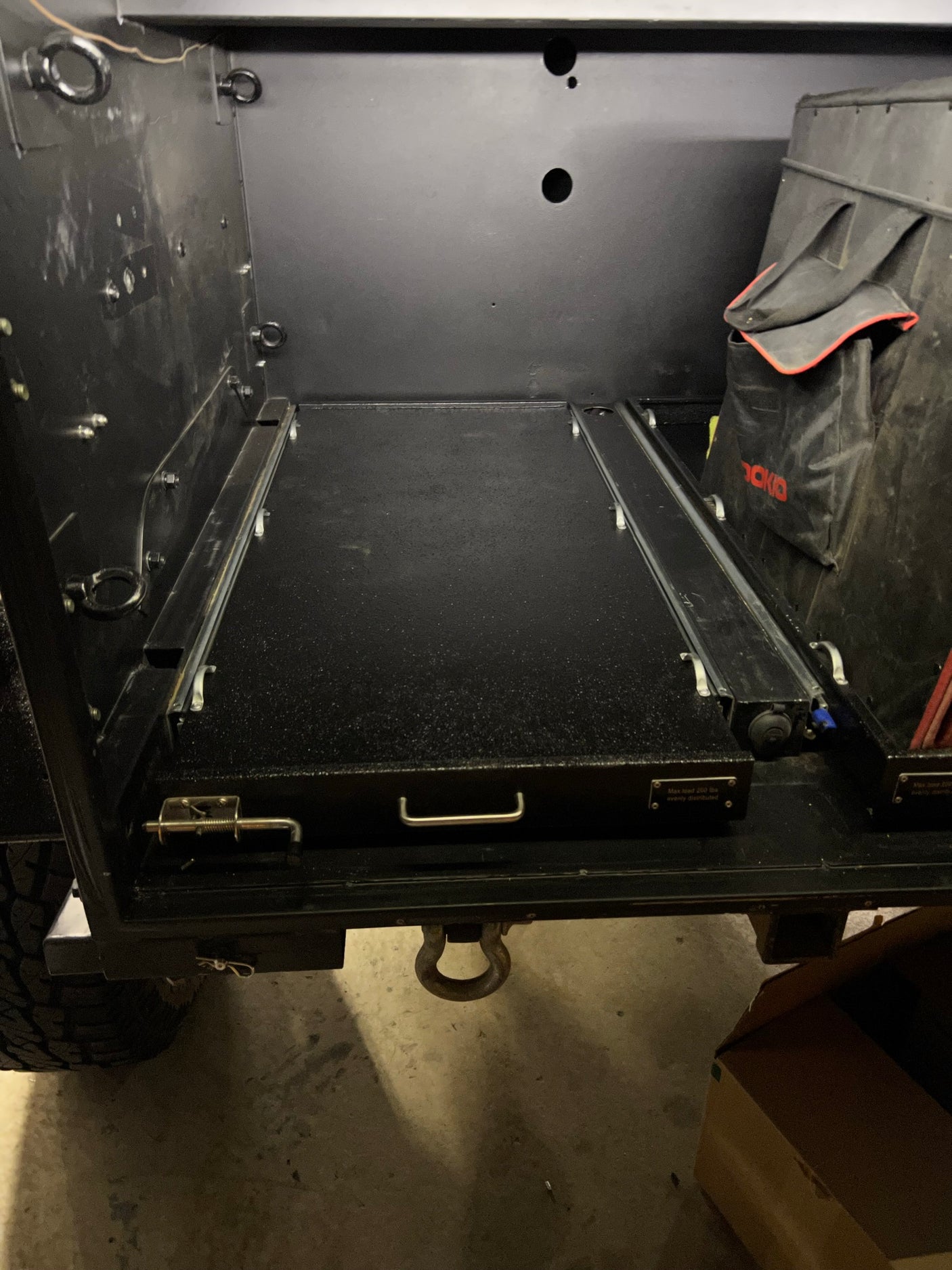Inside an RV rental: a durable, black cargo bay with a heavy-duty pull-out tray for organized gear storage. Max 200 lb load.