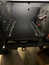 Inside an RV rental: a durable, black cargo bay with a heavy-duty pull-out tray for organized gear storage. Max 200 lb load.