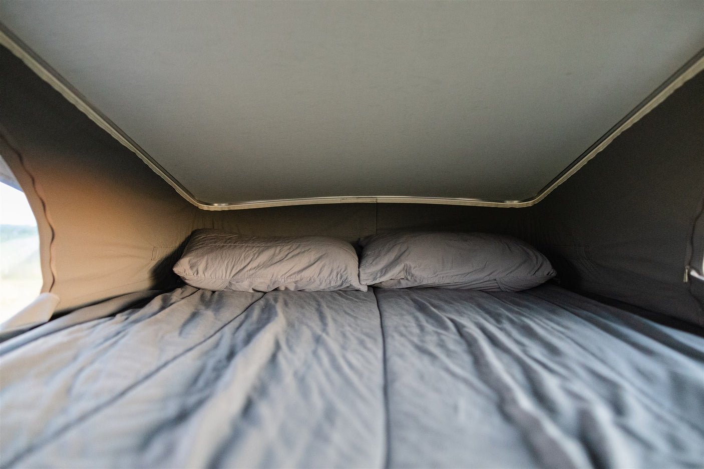 Comfortable sleeping area in an RV rental, featuring a bed with pillows under a pop-top roof.