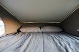 Comfortable sleeping area in an RV rental, featuring a bed with pillows under a pop-top roof.