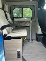 RV rental interior: Cream quilted seats, a removable table, and a vital SAFE-T-ALERT propane alarm for safety.