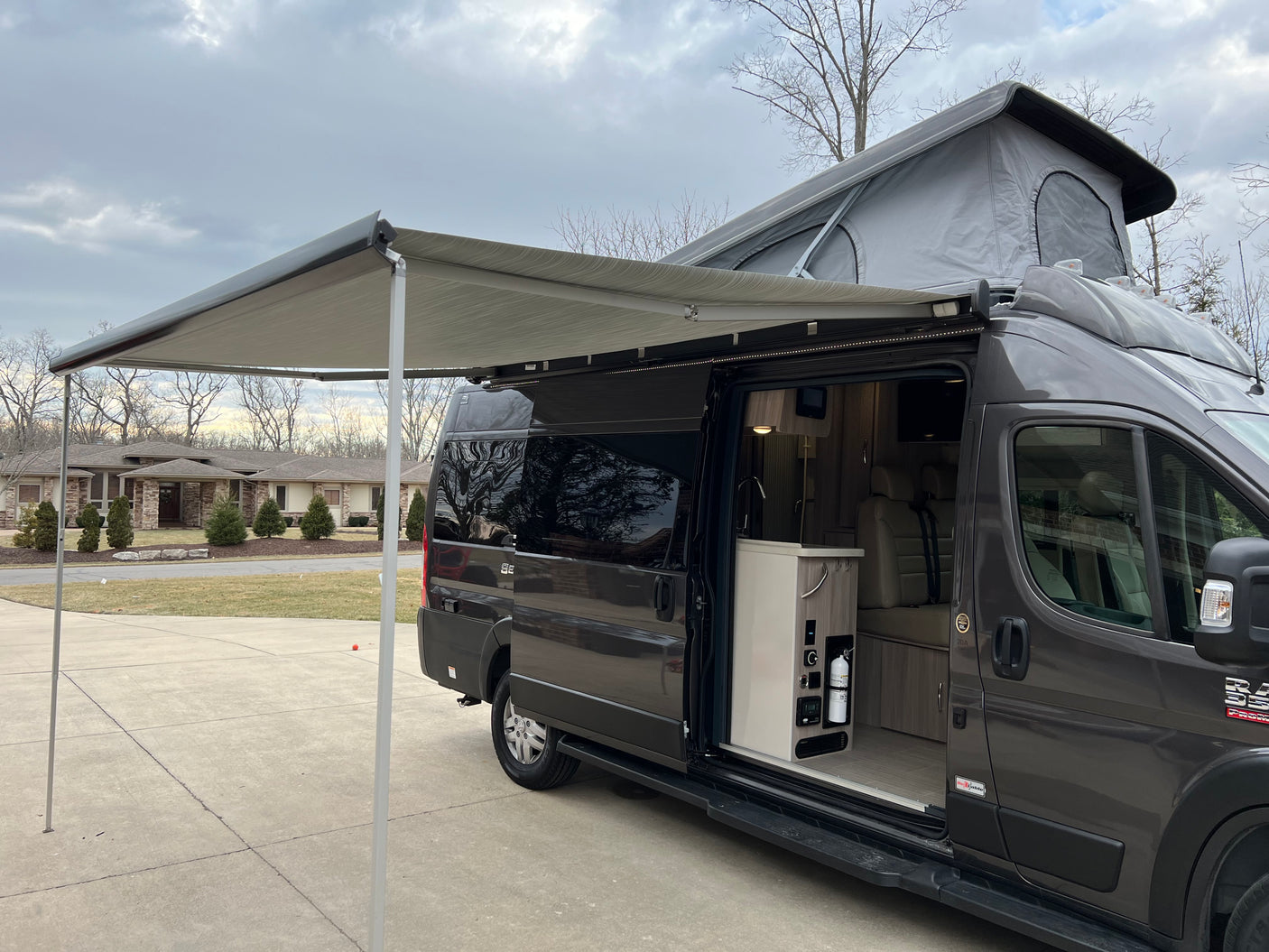 Explore this dark gray camper van with pop-top & extended awning. See the inviting interior of this rv rental.
