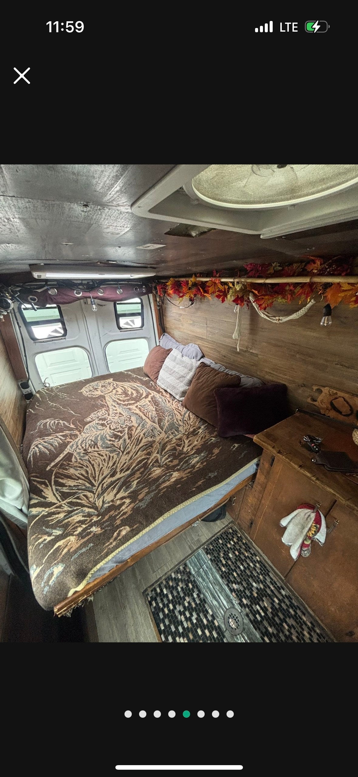 Inside this rv rental: A comfy bed with a tiger blanket, rustic wood paneling, ceiling fan, and charming fall decorations. — photo 2