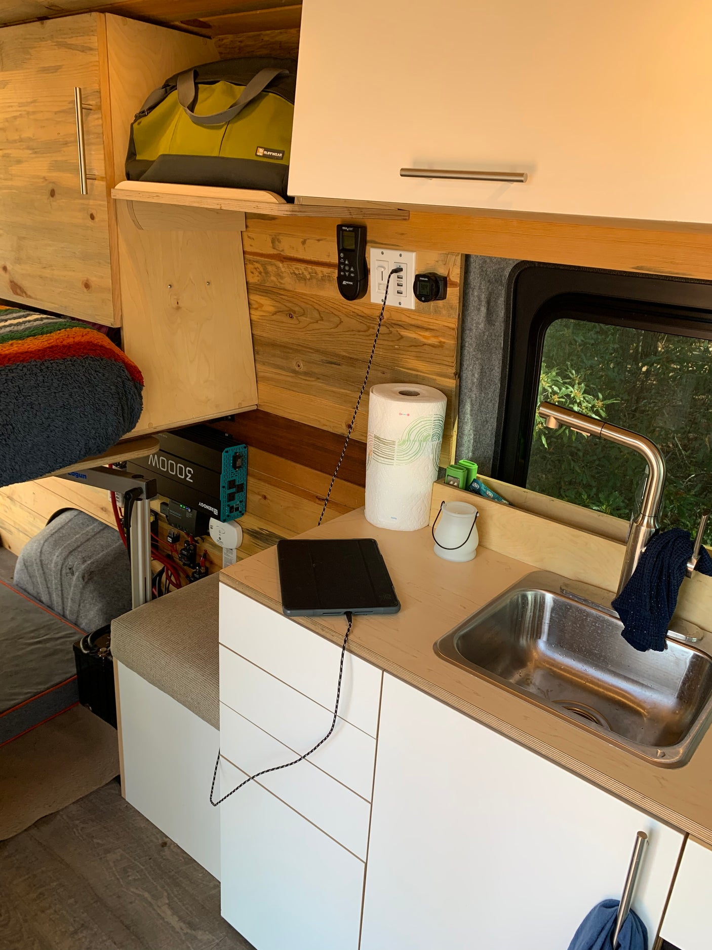 RV rental: Cozy camper van interior showing a kitchenette with sink, charging tablet, and power inverter for off-grid living.