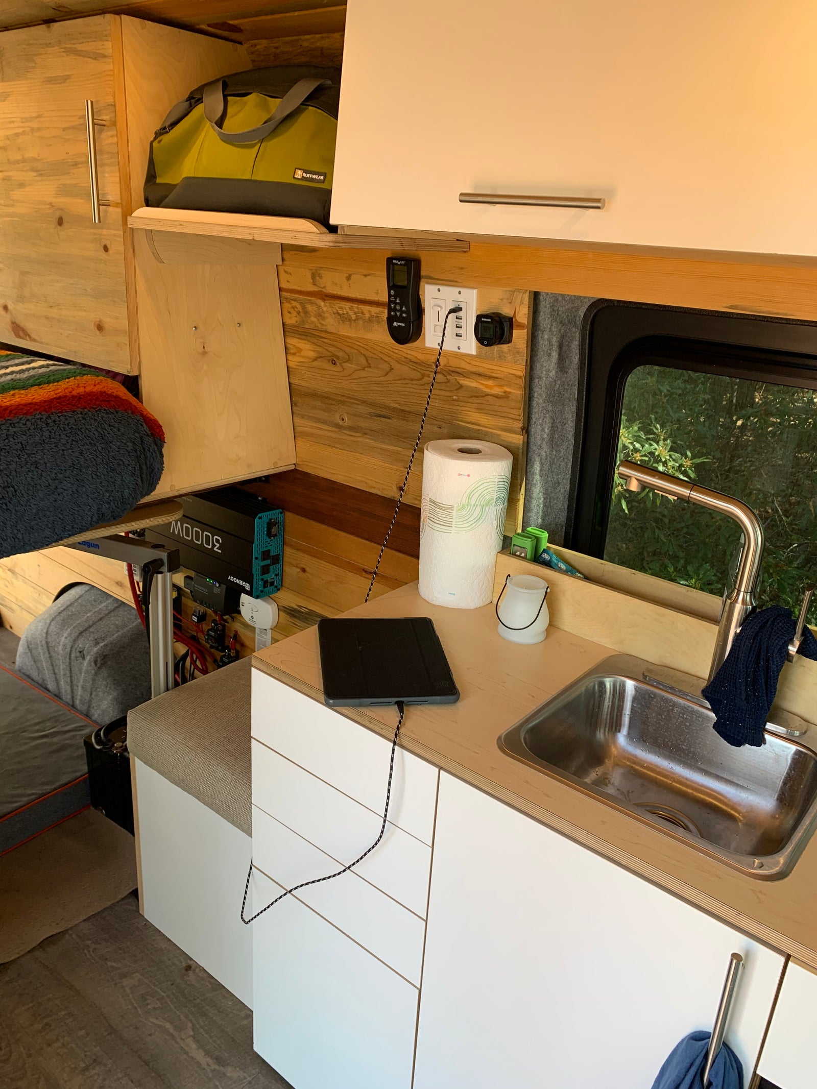 RV rental: Cozy camper van interior showing a kitchenette with sink, charging tablet, and power inverter for off-grid living.