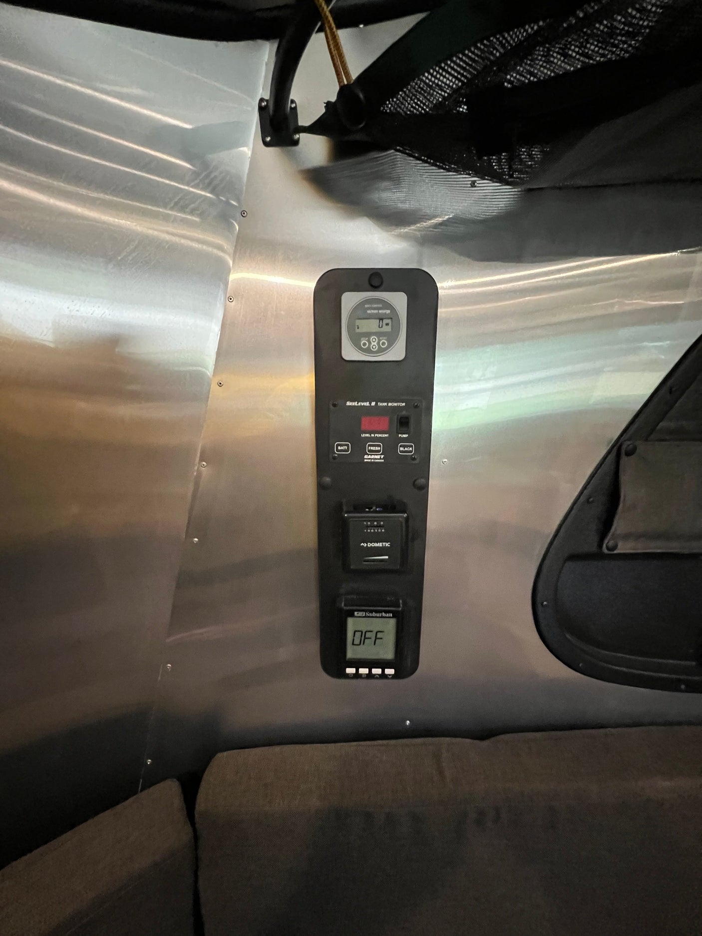 Essential RV rental control panel: SeeLevel tank monitor, Dometic system, and Suburban heater status (OFF) on metallic wall. Ready for camping.