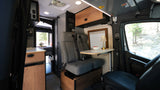 This rv rental's interior offers comfy passenger seats, a dining table, kitchenette, and bedroom for adventure travel.